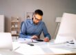 Homme effectuant sa comptabilité à son bureau.