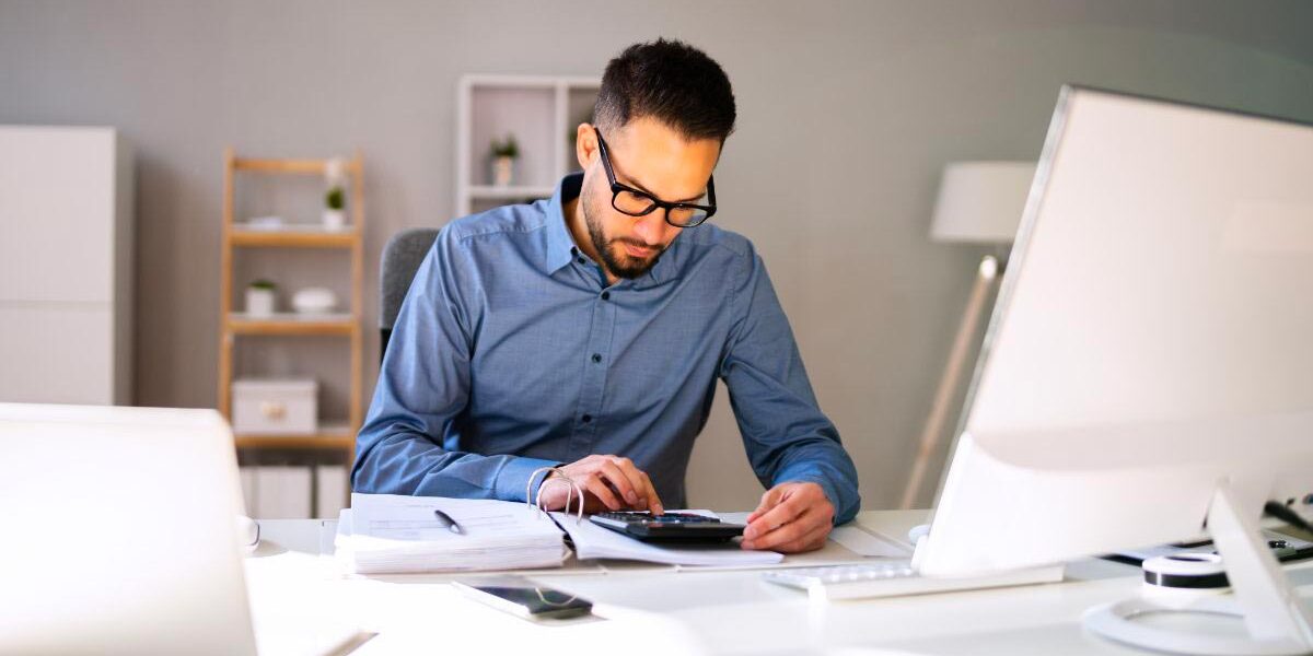 Homme effectuant sa comptabilité à son bureau.