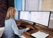 "Une professionnelle travaillant sur un écran incurvé affichant des factures électroniques, symbolisant la digitalisation et l’automatisation des processus de facturation dans un bureau moderne.