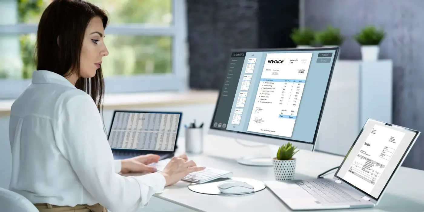 bufiscom-peppol-mercurius-facturation-electronique Une femme professionnelle utilisant un logiciel de facturation électronique sur plusieurs écrans dans un bureau moderne, illustrant le concept de digitalisation et de gestion des factures en ligne.
